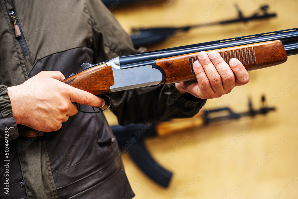 A customer's hands on an over and under shotgun at the counter